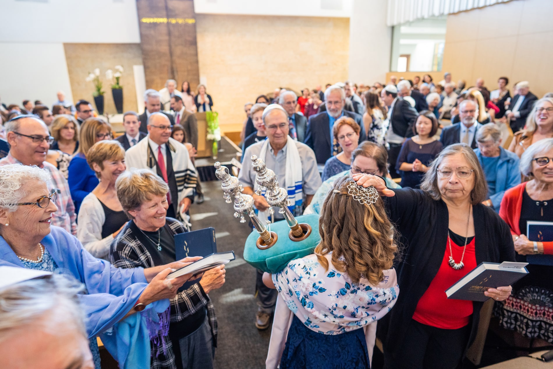 A group of people gather around the Torah scroll